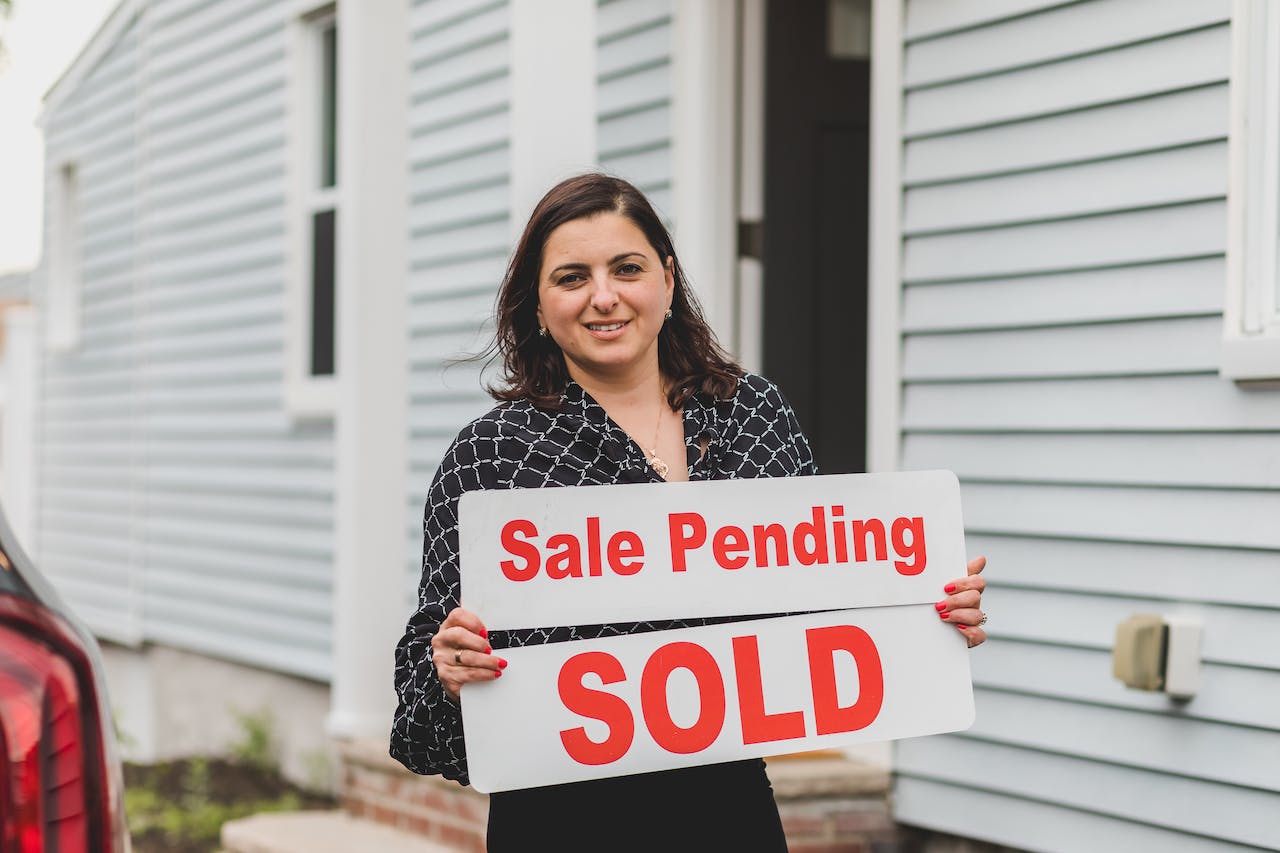 person holding for sale sign and sale pending sign