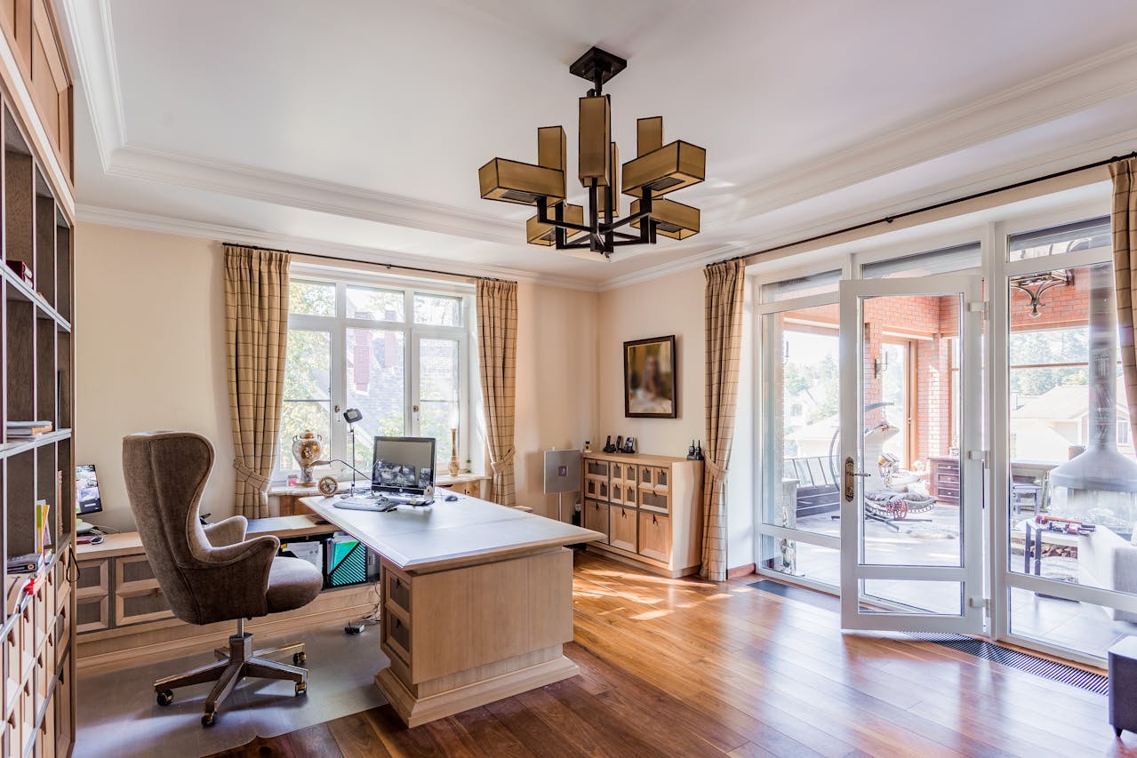 Modern home office with desk, ergonomic chair, and natural light from a side window. Image by Pexels
